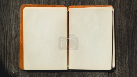 Foto de Bloc de notas en una mesa de madera vista de ángulo alto. Abre bloc de notas con papel en blanco. Copia espacio para texto. Enfoque selectivo incluido - Imagen libre de derechos