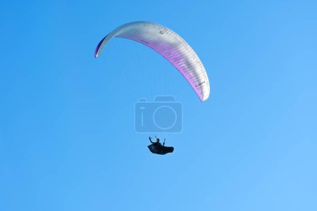 Photo for Batumi, Georgia - July 28 2022: Man is flying on a paraglider and waving his hand against the background of a bright blue sky - Royalty Free Image