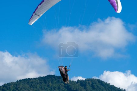 Foto de Batumi, Georgia - 28 de julio de 2022: El hombre vuela en un parapente y agita su mano contra el fondo de un cielo azul brillante - Imagen libre de derechos