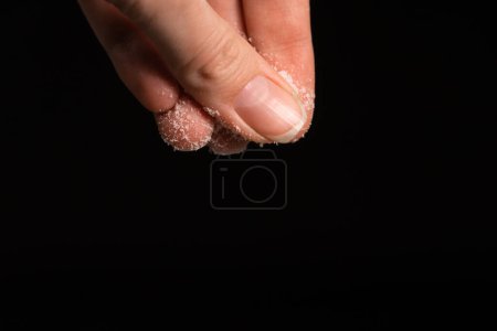 Foto de Los dedos femeninos espolvorean sal sobre un fondo negro, copian el espacio. Macrofotografía - Imagen libre de derechos