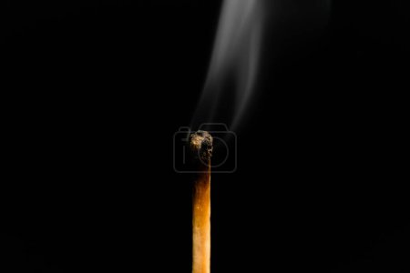 Foto de Una cerilla iluminada con humo sobre un fondo negro, macrofotografía. Un fósforo apagado con humo. - Imagen libre de derechos