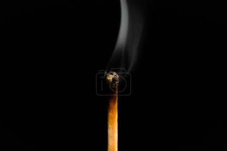 Téléchargez les photos : Un match éclairé avec de la fumée sur fond noir, macro photographie. Un match éteint avec la fumée. - en image libre de droit