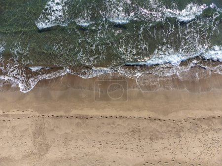Téléchargez les photos : Vue par drone sur la plage de sable et les vagues sur la mer par une journée ensoleillée, vue sur le dessus. Paysage marin d'été de l'air. Concept et idée de voyage - en image libre de droit