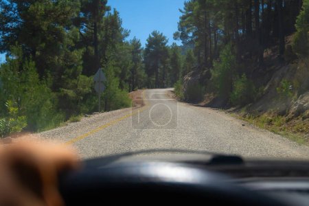 Téléchargez les photos : Conduire une voiture sur une route de montagne à la première personne. Vue de la voiture du siège du conducteur à la route sur une serpentine par une journée ensoleillée. Concept de voyage en voiture - en image libre de droit