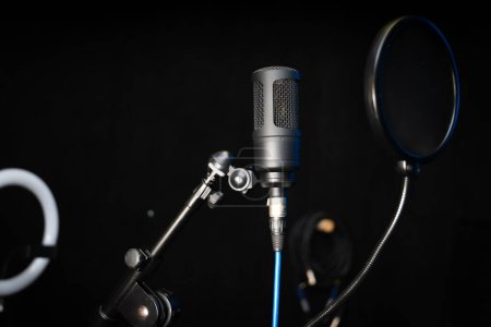 Téléchargez les photos : Gros plan d'un microphone professionnel de studio à condensateur sur fond noir dans un studio de musique. - en image libre de droit