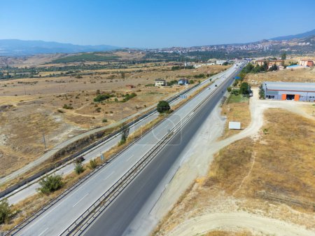 Téléchargez les photos : Vue de dessus d'une route asphaltée avec voitures, champs, montagnes près de la ville par une journée ensoleillée, Turquie. - en image libre de droit