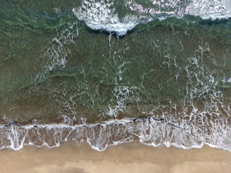 Téléchargez les photos : Vue par drone sur la plage de sable et les vagues sur la mer par une journée ensoleillée, vue sur le dessus. Paysage marin d'été de l'air. Concept et idée de voyage - en image libre de droit
