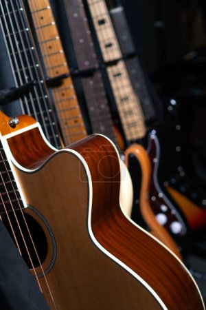 Téléchargez les photos : Gros plan de belles guitares debout dans une rangée près du mur dans un studio de musique ou dans un magasin, mise au point sélective. Photo verticale - en image libre de droit