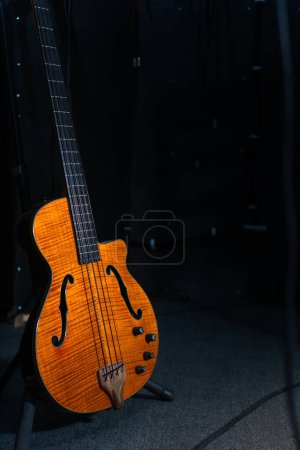 Téléchargez les photos : Gros plan d'une belle guitare électronique sur le sol dans le studio, éclairée par la lumière sur la scène, espace de copie. Photo verticale - en image libre de droit