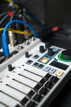 Close-up image of hand adjusting mixer knob for volume control during live studio performance. Mixer features multiple knobs and buttons for precise audio mix adjustments.