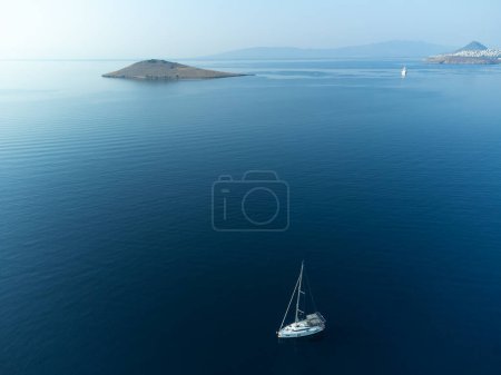 Téléchargez les photos : Un yacht avec une voile blanche en pleine mer, vue depuis un drone. Beau yacht de luxe avec voiles naviguant sur des vagues bleues. Vue depuis un drone du yacht sur l'eau bleue. - en image libre de droit