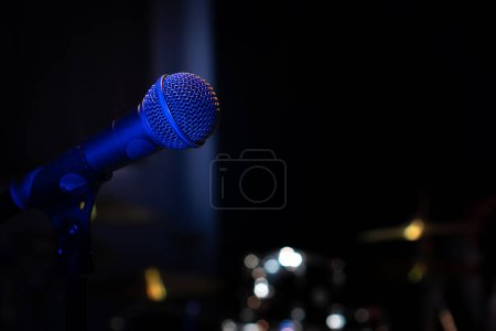 Gros plan d'un microphone avec rétroéclairage bleu dans un studio de musique, lors d'un concert dans l'obscurité, espace de copie