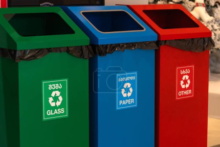 Foto de Primer plano de los botes de basura verdes, azules y rojos para el vertido separado de vidrio, papel y otra basura en la tienda. Concepto de eliminación adecuada de residuos. - Imagen libre de derechos