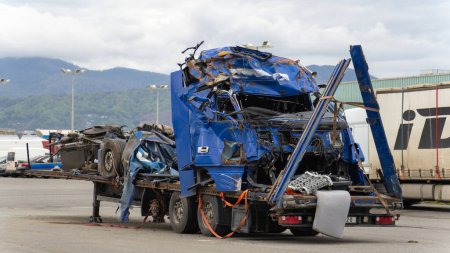 Cabine de camion bleu et semi-remorque sur une plate-forme de remorquage dans le stationnement après un accident grave.