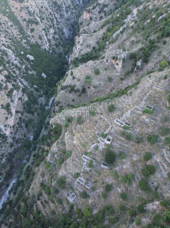 Photo for Aerial view of Abandoned stoned houses and mills with mechanical press in Mani area at Ridomo Gorge. Natural scenery from the famous Ridomo gorge in Taygetus mountain, Messenia in Greece - Royalty Free Image