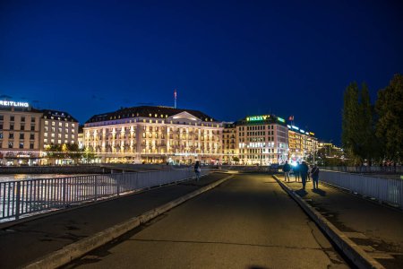 Téléchargez les photos : Genève, Suisse - 30 août 2023 : Fleuve Rhône et vue panoramique sur les façades des bâtiments de la ville de Genève illuminées la nuit à Genève en Suisse - en image libre de droit