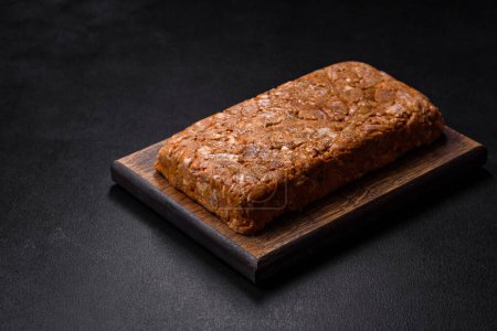 Photo for Tasty meat brawn or roll on a wooden cutting board with spices and herbs on a dark concrete background - Royalty Free Image