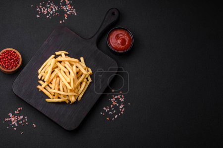Photo for Delicious crispy french fries with salt and spices on a dark concrete background. Unhealthy food, fast food - Royalty Free Image
