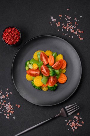 Salat aus frischem und gedämpftem Gemüse Kirschtomaten, Brokkoli, Karotten und Spargelbohnen auf dunklem Betongrund