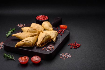Photo for Delicious pancakes triangular shape with meat, salt and spices on a dark concrete background - Royalty Free Image