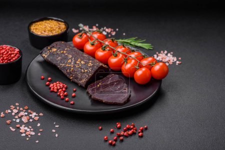 Photo for Delicious smoked Armenian basturma with spices and herbs sliced on a dark concrete background - Royalty Free Image