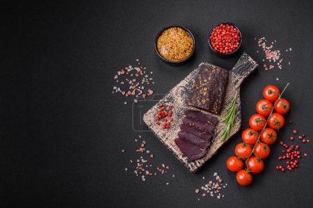 Photo for Delicious smoked Armenian basturma with spices and herbs sliced on a dark concrete background - Royalty Free Image