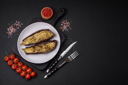 Photo for Delicious eggplant cut into two halves baked with salt, spices and herbs on a dark concrete background - Royalty Free Image