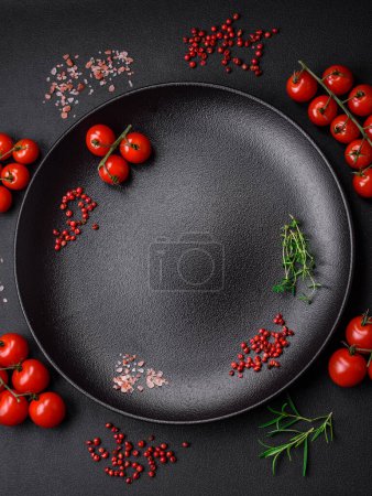 Photo for Ingredients for cooking cherry tomatoes, salt, spices and herbs on a dark concrete background - Royalty Free Image