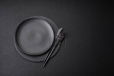 Photo for Empty black plate over dark stone background with copy space. Top view - Royalty Free Image