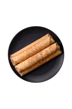 Téléchargez les photos : Délicieux rouleaux de gaufrettes croustillantes avec garniture crème aux noix sur fond de béton foncé - en image libre de droit