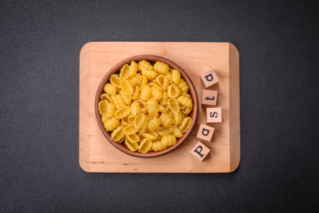Photo for Raw durum wheat gnocchi pasta with salt and spices in a ceramic plate on a dark concrete background - Royalty Free Image