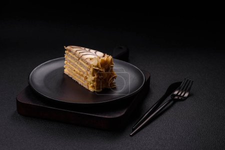 Piece of delicious sweet esterhazy cake with nuts and cream on a dark concrete background