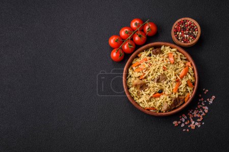 Téléchargez les photos : Délicieux pilaf aux légumes, sel, épices et herbes dans une assiette en céramique sur fond de béton foncé - en image libre de droit