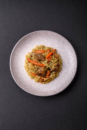Téléchargez les photos : Délicieux pilaf aux légumes, sel, épices et herbes dans une assiette en céramique sur fond de béton foncé - en image libre de droit