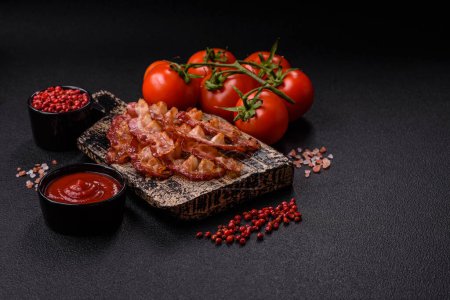 Photo for Delicious fresh fried bacon with salt and spices on a dark background as an ingredient for preparing a hearty breakfast - Royalty Free Image