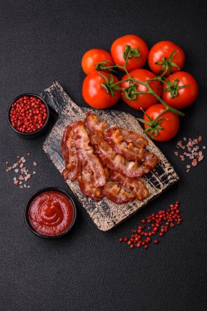 Photo for Delicious fresh fried bacon with salt and spices on a dark background as an ingredient for preparing a hearty breakfast - Royalty Free Image