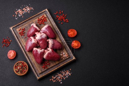 Raw turkey or chicken hearts with salt and spices on a dark concrete background
