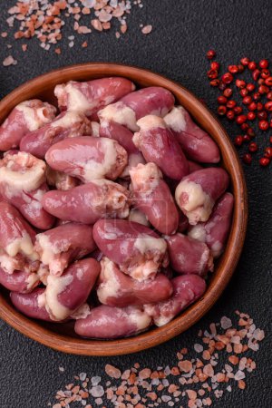 Raw chicken hearts with salt, spices and herbs on a dark concrete background