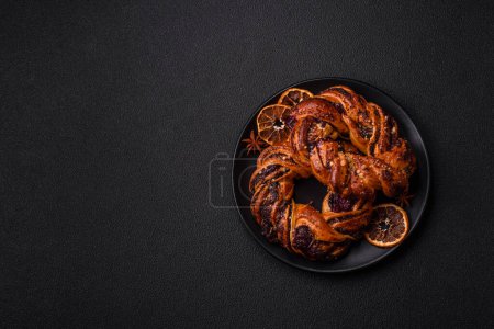 Téléchargez les photos : Délicieux pain frais cuit au four avec des graines de pavot et des baies en forme d'anneau sur un fond de béton foncé - en image libre de droit