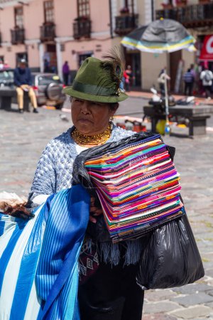 Foto de Quito, Ecuador, 3 de enero de 2023: Mujeres de las comunidades indígenas de Cotopaxi venden sus tapices a turistas, todo el año, en el centro histórico de Quito. - Imagen libre de derechos