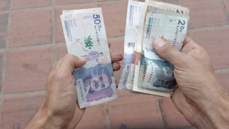Téléchargez les photos : Mains comptant les billets de banque Peso Colombien - inflation et croissance économique de l'un des pays les plus pauvres d'Amérique du Sud - en image libre de droit