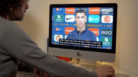 Foto de Europa, Milán 2022 - Ver las noticias de televisión en un ordenador portátil - Entrevista jugador de fútbol Cristiano Ronaldo - Imagen libre de derechos