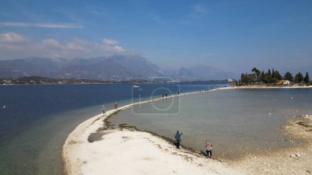 Foto de Italia, Lago de Garda, Isla de San Biagio, Isla Conejo - las aguas poco profundas del lago le permiten caminar y llegar a la isla a pie - emergencia de agua en Lombardía, la sequía baja del nivel del agua - Imagen libre de derechos