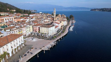 Photo for Europe, Italy, Brescia , Garda lake , Salo' drone aerial view of the village with church and lake with blue water - Italian Republic from 1943 to 1945 during the reign of Benito Mussolini fascist - Royalty Free Image