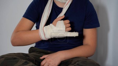 Photo for Boy child 8 years old child breaks by fracturing the finger of his right hand and wears a rigid plaster bandage to heal the fracture - lifestyle in an apartment after a typical childhood injury - Royalty Free Image