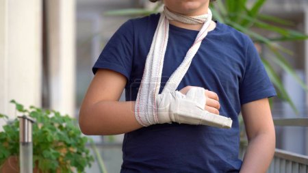 Photo for Boy child 8 years old child breaks by fracturing the finger of his right hand and wears a rigid plaster bandage to heal the fracture - lifestyle in an apartment after a typical childhood injury - Royalty Free Image