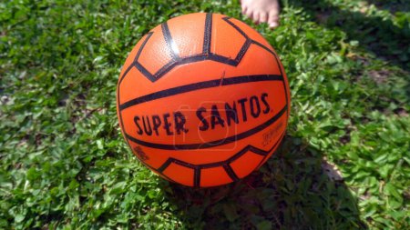 Photo for Italy 2023 - Old vintage orange football soccer ball Super Santos - playing football in childhood in a green garden - Royalty Free Image