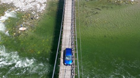 Téléchargez les photos : Voiture passe sur un pont tibétain en bois qui rejoint les rives de la rivière - vue depuis le drone dans les montagnes Alagna Val Sesia Piémont - voyage concept voyage aventure voyage naturel - en image libre de droit