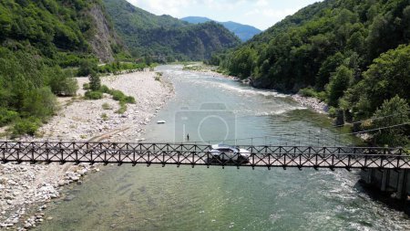 Téléchargez les photos : Voiture passe sur un pont tibétain en bois qui rejoint les rives de la rivière - vue depuis le drone dans les montagnes Alagna Val Sesia Piémont - voyage concept voyage aventure voyage naturel - en image libre de droit