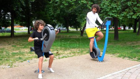 Foto de Italia, Milán - Padre e hijo niño niño 9 años de edad hacer gimnasia gimnasio en un parque con el área de equipos de peso - ejercicios físicos actividades deportivas y la dieta de preparación de verano - Imagen libre de derechos